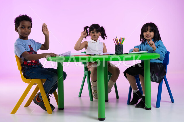 تقنيات الرسم لمرحلة ما قبل المدرسة, النظر إلى الكاميرا والاستمتاع بممارسة المهارة الفنية, تنمية المهارات الحركية والنشاطات الفنية، أنشطة ترفيهية في الروضة، بورتريه لأطفال عرب خليجيين سعوديين يرتدون الزي الكاجوال يمارسون نشاط تلوين الرسومات، خلفية وردية