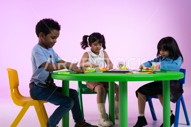 النشاطات الفنية والحركية, قضاء أوقات ممتعة ومفيدة في الروضة, تنمية الجانب الحركي والابتكاري لدى الأطفال، تعلم صنع أشكال ومجسمات باستخدام العجينة الملونة، بورتريه لأطفال عرب خليجيين سعوديين يبدعون بنشاط اللعب بالمعجون الملون، خلفية وردية