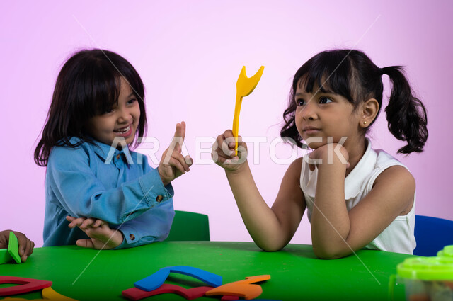 دمج المتعة والفائدة في الروضة، تعليم وإبداع وتنمية مهارات في رياض الأطفال، بورتريه لأطفال عرب خليجيين سعوديين يرتدون الزي الكاجوال يتعلمون الأرقام عن طريق اللعب والمرح، إيماءات تدل على الفرح والسعادة والسرور، خلفية وردية.