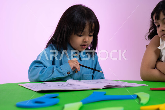 تعلم الأرقام والأعداد العربية وأشكالها، نشاطات ترفيهية وتعليمية تساعد على تنمية القدرات الفكرية، المشاركة والتعاون بين أطفال الروضة في تعلم الرياضيات، بوتريه مقرب لطفل عربي خليجي سعودي يرتدي الزي الكاجوال يتعلم الحساب، خلفية وردية