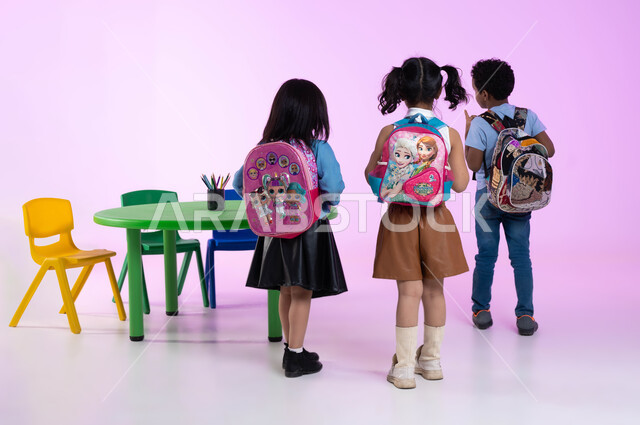 تنمية المهارات و التعليم لابداع، أماكن لحضانة الأطفال و الاعتناء بهم، قرطاسية وحقائب مدرسية للطلاب، الاستعداد والتجهيز للعودة إلى المنزل، بورتريه من الخلف لأطفال عربيين خليجيين سعوديين يرتدون الزي الكاجوال وحقيبة الظهر، صورة لكامل الجسم، خلفية وردية