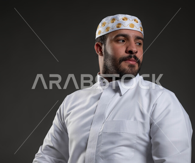 الخشوع و التضرع لله، الشعور بالسكينة والطمأنينة، بورتريه مقرب لرجل عربي خليجي سعودي يرتدي الثوب والقبعة الإسلامية البيضاء يجلس على السجادة يقوم بالسلام لإنهاء الصلاة، آداء الفرائض والعبادات، مفهوم أركان الإسلام، خلفية رمادية