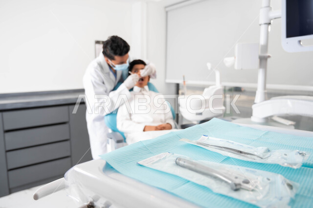 أدوات طبية نظيفة ومعقمة, طفل عربي خليجي سعودي يرتدي الزي التقليدي في موعد لعلاج اسنانه عند طبيب الاسنان ، طبيب سعودي خليجي عربي يفحص اسنان المريض، عيادة أسنان خاصة، مفهوم الطب والرعاية الصحية