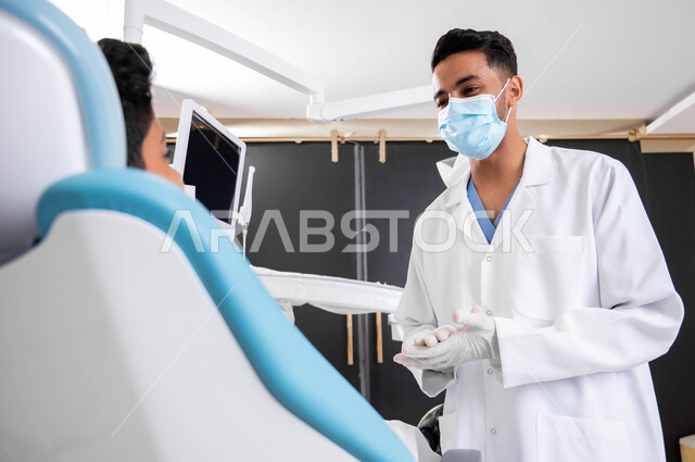 التعليمات والإرشادات الطبية، طبيب أسنان يتحدث مع مريضه بإيماءات الاطمئنان، ولد عربي خليجي سعودي يجلس في عيادة سنية يتلقى النصائح، العناية والاهتمام بالصحة الفموية، معالجة الأسنان من النخور والتسوس، الزيارة الدورية للعيادات الصحية