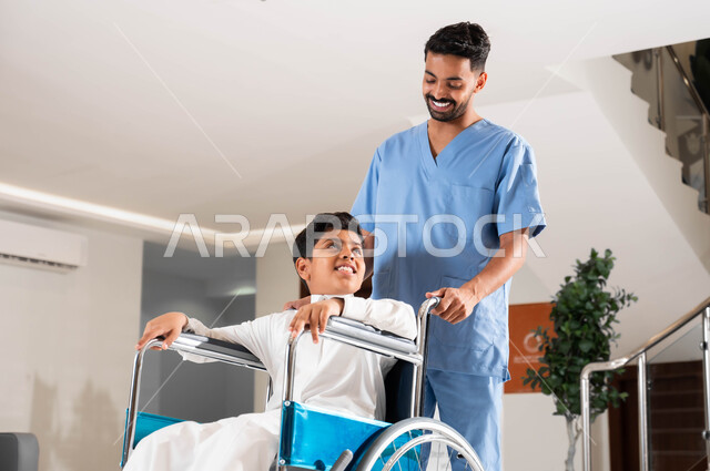 توفير معدات تساعد على الحركة ,الاهتمام بالجانب النفسي لأصحاب الهمم ,شركات سعودية مختصة في التمريض المنزلي ,الاعتناء بذوي الاحتياجات الخاصة, ممرض عربي سعودي خليجي يرتدي الزي الخاص بالعمل يقوم بمساعدة ولد سعودي مقعد يجلس على كرسي متحرك في التنقل داخل المنزل