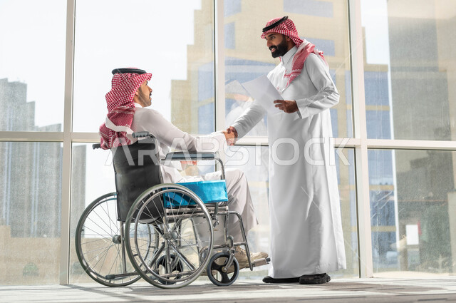 رجلان عربيان سعوديان خليجان  يرتديان الشماغ والثوب السعودي التقليدي يقومان بمصافحة بعضهما، التعرف على الزملاء الجدد في مقر الشركة، عقد الاتفاقات والصفقات التجارية، اتاحة المجال امام ذوي الهمم للدخول الى مجال العمل، الترحيب والاستقبال وبناء العلاقات الاجتماعية