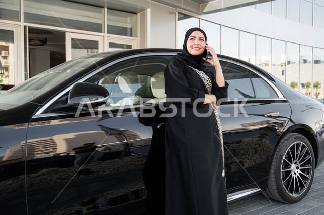 القيادة للذهاب الى العمل، استخدام الاجهزة التقنية الحديثة، سيده أعمال عربية خليجية سعودية ترتدي الحجاب والعباءة تستند على سيارتها تقوم بإجراء مكالمة هاتفية, مفهوم الاستقلال والحرية، اعتماد المرأه على نفسها في التنقل والمواصلات