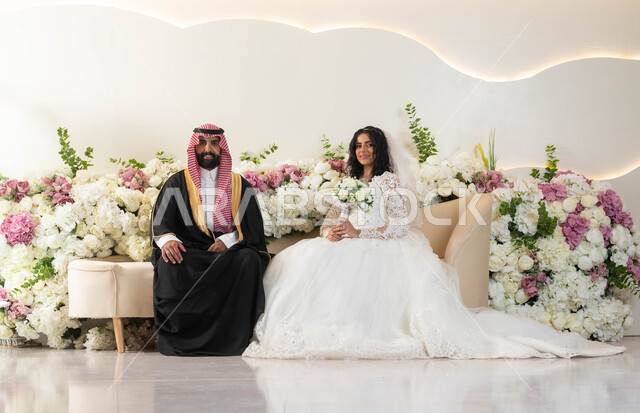 أصالة العادات و التقاليد، مفهوم الاستقرار و تكوين أسرة، الفرح و السرور في يوم الزفاف، اجمل إطلالة لرجل عربي وسيم يرتدي الزي الرسمي والبشت التقليدي، صورة لعروسة عربية خليجية سعودية ترتدي فستان زفاف أبيض تمسك بيدها باقة ورد، مراسم الاعراس و المناسبات في المملكة