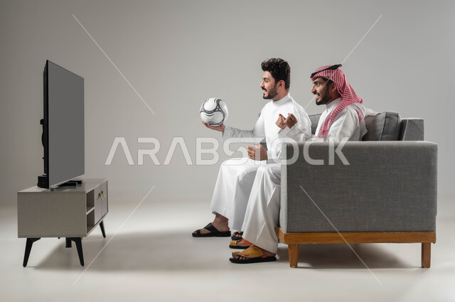 التشجيع بحماس وتشويق, قضاء اوقات الفراغ الممتعة مع الاصدقاء, الانتصار بتحقيق الاهداف, بورتريه لرجلان عربيان سعوديان خليجيان, ايماءات السعادة والفرح تعبيرا عن الفوز, الشغف بالانشطة الترفيهية, المباريات والالعاب الرياضية, خلفية رمادية