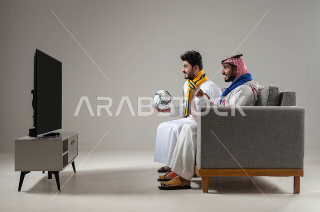 تعابير تدل على الحماس والتشويق, قضاء اوقات ممتعة ومسلية مع الاصدقاء, الشغف بمتابعة الانشطة الرياضية, البشاشة والاندماج لتحقيق الفوز والانتصار, بورتريه لرجلان عربيان سعوديان خليجيان يرتديان اوشحة تشجيعية لفرق كرة القرم, خلفية رمادية