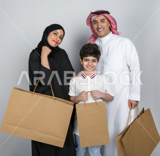 Portrait of a happy Saudi Arabian Gulf family carrying shopping bags, buying gifts, entertainment and shopping, day shopping, White Friday