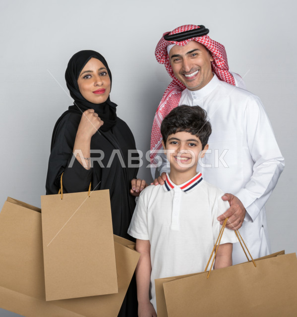 Portrait of a happy Saudi Arabian Gulf family carrying shopping bags, buying gifts, entertainment and shopping, day shopping, White Friday