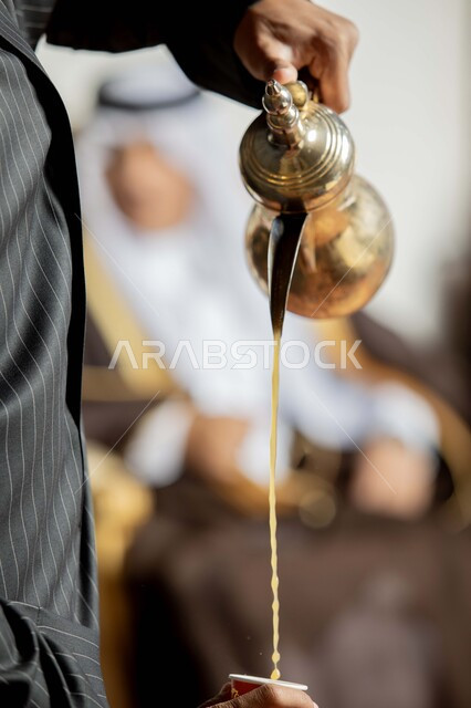 العادات والتقاليد العربية الأصيلة, حسن الاستقبال وإكرام الضيوف, صورة مقربة لرجل عربي خليجي سعودي يرتدي الثوب التقليدي يقوم بصب القهوة, منتجات عربية محلية وطنية, الأصالة والتراث في المملكة العربية السعودية, الضيافة في الأعياد والمناسبات