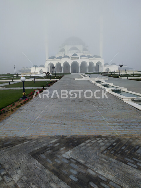 The outer courtyard of the Sharjah Grand Mosque in the United Arab Emirates, architectural art and designs in the Arab-Islamic style, famous religious landmarks in the Emirate of Sharjah, foggy skies and winter atmosphere, worship and getting closer to God, Islamic background