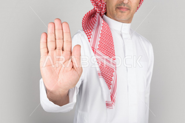 Portrait of a Saudi Arabian Gulf man, with two hands indicating pause, white background