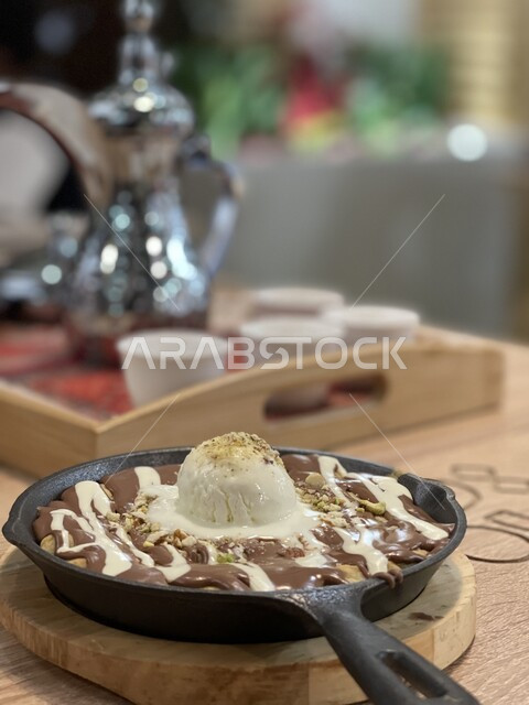حلويات وسكريات باردة شرقية و لذيذة، صورة مقربة لطبق من حلا كيك الشوكولاته المزينة بقطعة آيس كريم بنكهة الفانيليا، قطع الحلوى الشهية، مفهوم الضيافة التقليدية في السعودية