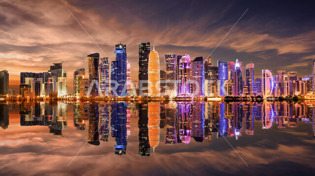 Urban progress and development, the reflection of the light of towers and skyscrapers on the water in the city of Doha, the architectural art of facilities and buildings illuminated at night, famous tourist places and areas, the importance of the role of tourism in the city of Qatar, enjoying the quiet atmosphere at night