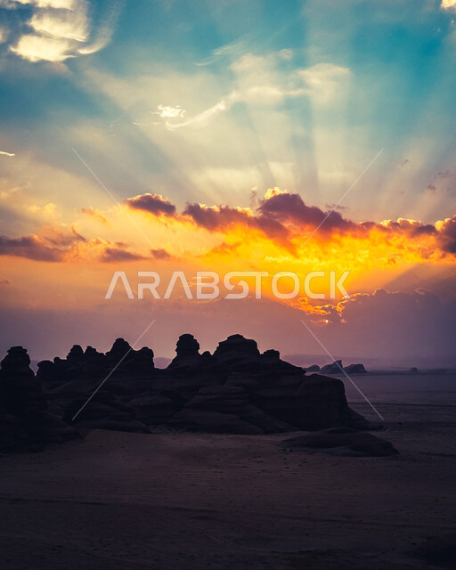 The view of the sunset behind the clouds in the sky of the Kingdom of Saudi Arabia, the terrain in the mountain peaks and heights, famous natural tourist places, rock sculpture in desert areas, a close-up of the rock formations and formations in Al-Ula Governorate, ancient civilization and historical monuments