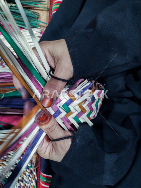 التراث والأصالة في دولة الامارات العربية المتحدة, حرف يدوية تاريخية, أعمال وصناعات قديمة, استخدام أوراق النخيل المجففة في صناعة السلل, منتجات محلية وطنية اماراتية, مهن شعبية تقليدية, صورة مقربة ليد إمرأة عربية خليجية اماراتية تقوم بجدل سعائف الخوص