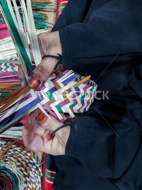 التراث والأصالة في دولة الامارات العربية المتحدة, حرف يدوية تاريخية, أعمال وصناعات قديمة, استخدام أوراق النخيل المجففة في صناعة السلل, منتجات محلية وطنية اماراتية, مهن شعبية تقليدية, صورة مقربة ليد إمرأة عربية خليجية اماراتية تقوم بجدل سعائف الخوص