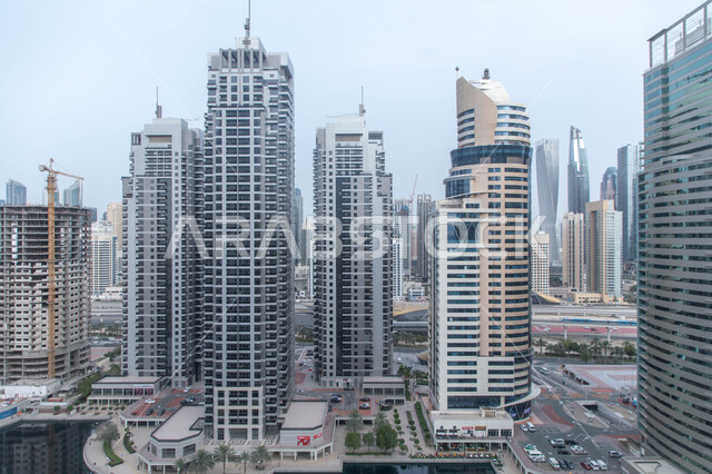 Architectural engineering in a modern and advanced style for constructing buildings and skyscrapers in the city of Dubai, towers overlooking the yacht marina in Dubai Marina on the coast of the Arabian Gulf, famous tourist attractions in daylight, commercial establishments in the city of the United Arab Emirates