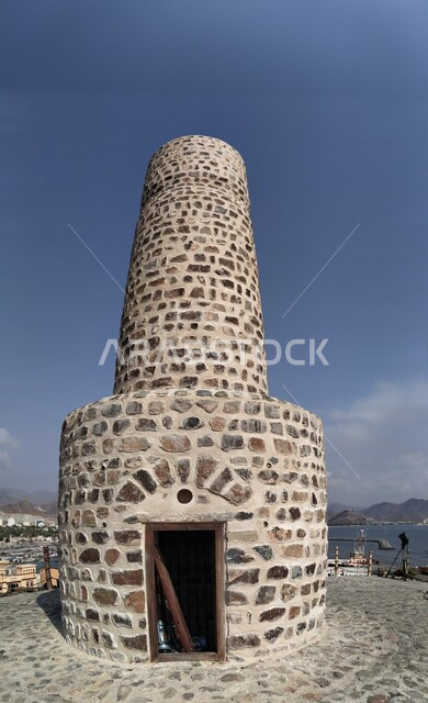 الفن الهندسي المعماري على الطراز الفريد المميز, برج العدواني الأثري المبني من الحجارة في مدينة خورفكان في إمارة الشارقة فى الامارات العربية المتحدة, المعالم التاريخيه القديمة ,الأماكن السياحية التراثية, خلفية السماء الزرقاء