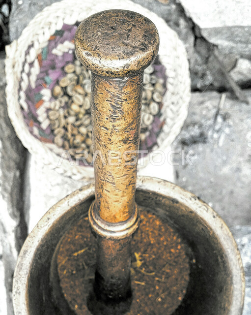 Traditional popular heritage tools, a close-up photo of a manual copper grain mill, the use of a mortar bowl and stick for grinding in the Kingdom of Saudi Arabia, antique Gulf equipment