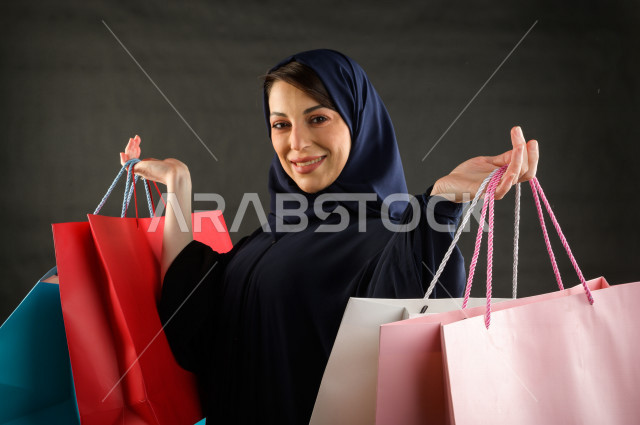 Portrait of a Saudi Arabian Gulf woman carrying shopping bags, buying gifts, entertainment and shopping, shopping day, White Friday