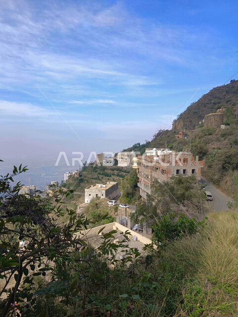 Residential buildings and ancient ancient houses in the mountains of Faifa Governorate in Jizan, natural landmarks and tourist places in the Kingdom of Saudi Arabia, green agricultural terraces and trees on the mountain peaks and heights, nature background