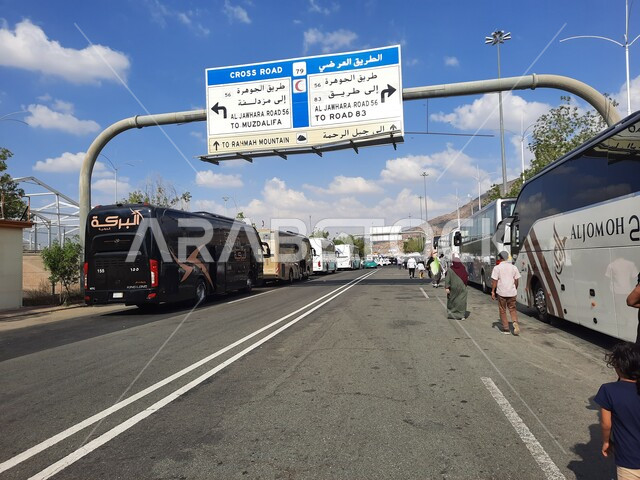 Transport buses and transportation on roads and streets, the concept of worship and getting closer to God, performing Hajj and Umrah rituals, sacred Islamic religious landmarks and places, signboards and guide boards for the way to Mount Mercy (Arafat) in Mecca during the Hajj season in the Kingdom of Saudi Arabia.