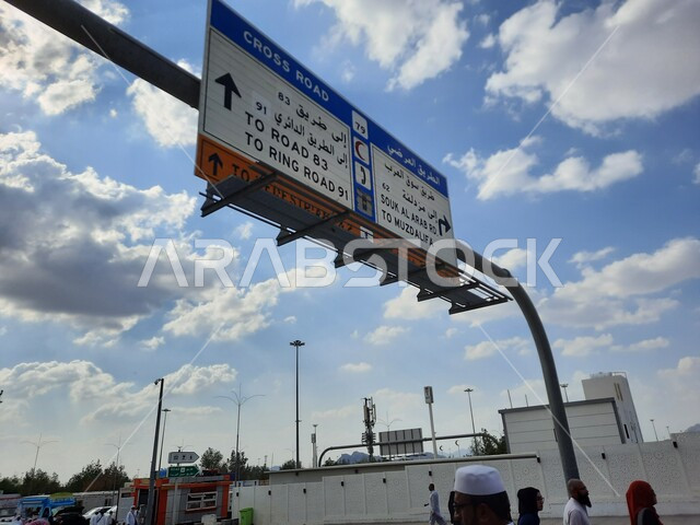 التوجه الى جبل الرحمة (عرفة) في مكة المكرمة في موسم الحج في المملكة العربيه السعودية، مفهوم العبادة والتقرب إلى الله ،اداء مناسك الحج والعمرة، معالم واماكن اسلامية دينية مقدسة، صورة مقربة  للافتات و لوحات ارشاديه، خلفية السماء الزرقاء مع الغيوم البيضاء