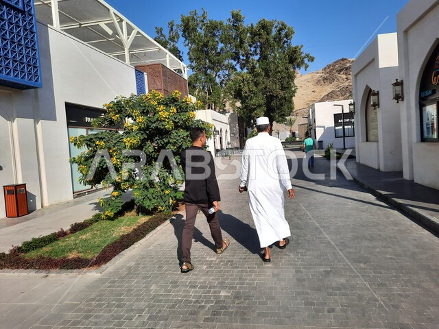 الفن الهندسي المعماري على الطراز الحديث في مكة المكرمة، صورة من الخلف لرجلان عربيان خليجيان سعوديان يتجولان في مركز حراء الثقافي بالقرب من جبل النور، أماكن إسلامية مقدسة، معالم سياحية مشهورة في المملكة العربية السعودية