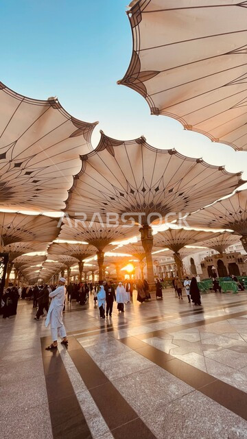 تجمع المسلمون امام المسجد النبوي الشريف، معالم دينية إسلامية مقدسة في المملكة العربية السعودية،  المظلات الإلكترونية للتظلل والحماية في ساحة الحرم النبوي في المدينة المنورة وقت غروب الشمس، أماكن لأداء فروض الصلوات والعبادة والتقرب الى الله