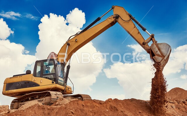 جرافة تعمل على رفع وتعبئة الرمال والحصى في النهار، مفهوم الهندسة والإنشاءات والتطوير، مهن ووظائف هندسية في السعودية، معمل تجميع الرمل والآلات الضخمة، قوة وتقنية عملية استخراج مواد البناء، آلات ومعدات ثقيلة