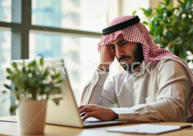 تعابير الحزن والتعب, تنظيم وإدارة الأعمال ضمن مقر الشركة, مفهوم ضغط العمل, صورة مقربة لرجل عربي خليجي سعودي يرتدي الشماغ والثوب التقليدي يضع يديه على رأسه يقوم باستخدام الحاسب المحمول, إيماءات الملل والضجر, وظائف ومهن مكتبية