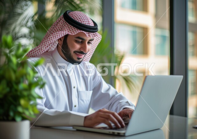 إيماءات السرور والفرح, بيئة العمل المريحة في الشركات السعودية, مهن ووظائف مكتبية, صورة مقربة لرجل عربي خليجي سعودي مبتسم يرتدي الشماغ والثوب التقليدي يقوم باستخدام الحاسب المحمول, مفهوم التركيز والتمعن, إدارة وتنظيم الأعمال ضمن مقر الشركة