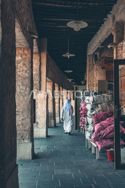 معالم دولة قطر السياحية المشهورة, أسواق شعبية تقليدية, مناطق جذب واستقطاب السائحين من شتى أنحاء العالم, صورة من الخلف لرجل عربي خليجي قطري يرتدي العمامة يتجول في سوق واقف التجاري في مدينة الدوحة