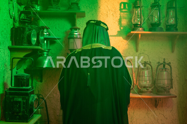 الفخر والاعتزاز بالهوية السعودية، المناسبات والأعياد الوطنية، صورة مقربة من الخلف لرجل عربي خليجي سعودي يرتدي العقال والبشت التقليدي يشاهد الفوانيس المعدنية، ذكرى تأسيس الدولة السعودية الاولى 22 فبراير، توارث حب التراث القديم من الأجداد، يوم بدينا 1727 م