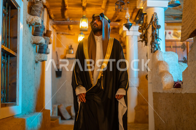 الاعتزاز بالهوية السعودية, الأعياد والمناسبات الوطنية في السعودية, إيماءات الثقة والحزم, يوم بدينا 1727 م، رجل عربي خليجي سعودي يرتدي البشت والعقال يتجول في أحد الأحياء التراثية الطينية المبنية على الطراز القديم, ذكرى تأسيس الدولة السعودية الأولى في 22 فبراير