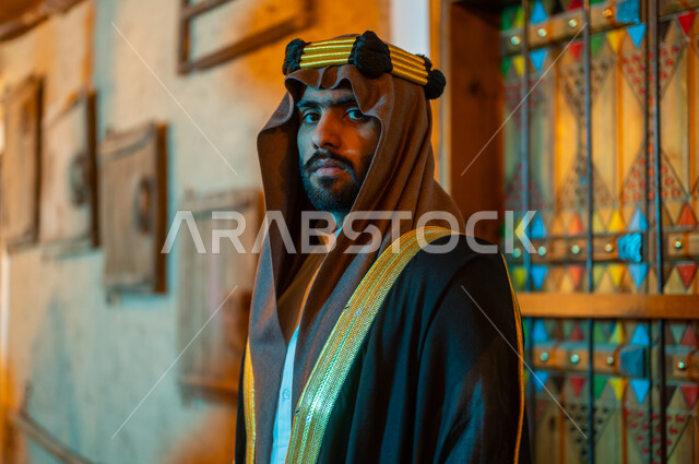 الأعياد والمناسبات الوطنية في السعودية, النظر الى الكاميرا بإيماءات الثقة والحزم, يوم بدينا 1727 م، صورة مقربة لرجل عربي خليجي سعودي يرتدي البشت والعقال يقف في أحد الأحياء التراثية الطينية المبنية على الطراز القديم, ذكرى تأسيس الدولة السعودية الأولى في 22 فبراير