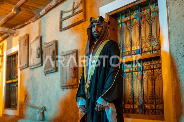 النظر الى الكاميرا بإيماءات الثقة والحزم, يوم بدينا 1727 م، الأعياد والمناسبات الوطنية في السعودية, رجل عربي خليجي سعودي يرتدي البشت والعقال يقف في أحد الأحياء التراثية الطينية القديمة المبنية على الطراز القديم,, ذكرى تأسيس الدولة السعودية الأولى في 22 فبراير