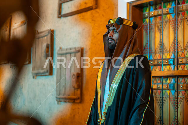 الوقوف بإيماءات الثقة والحزم والقوة, الأحياء والمنازل التراثية الشعبية الطينية القديمة, يوم بدينا 1727 م، الأعياد والمناسبات الوطنية في السعودية, صورة مقربة لرجل عربي خليجي سعودي يرتدي البشت والعقال ينظر الى شيء ما, ذكرى تأسيس الدولة السعودية الأولى في 22 فبراير
