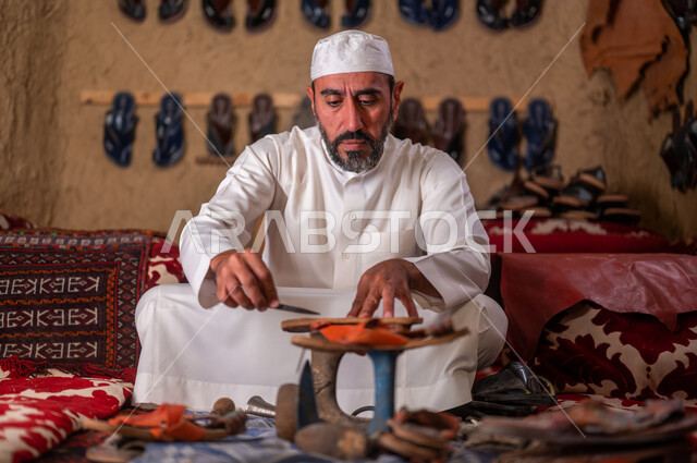 Old traditional professions and crafts, popular works and industries, Day of Our Day 1727 AD, shoe repair shop, a Saudi Arabian Gulf cobbler wearing the traditional dress and a white hat, making shoes and repairing them with appropriate tools, the anniversary of the founding of the first Saudi state, February 22