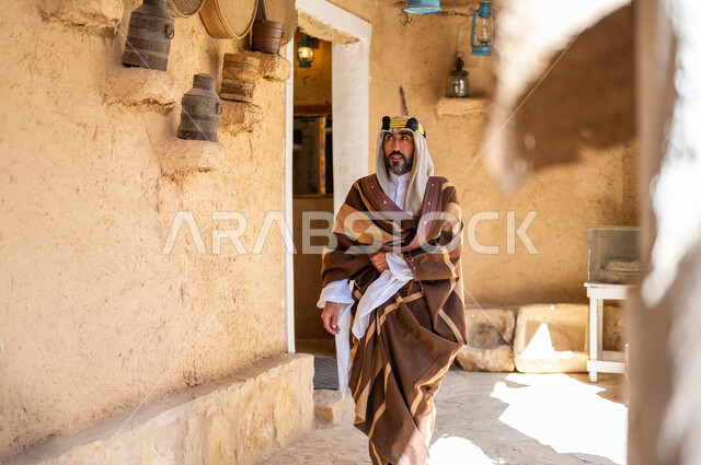 يوم بدينا 1727 م، الفخر والاعتزاز بالهوية السعودية، المناسبات والأعياد الوطنية، رجل عربي خليجي سعودي يرتدي العقال والبشت التقليدي في منزل طيني قديم، ارتداء الأزياء الشعبية في ذكرى تأسيس الدولة السعودية الاولى 22 فبراير