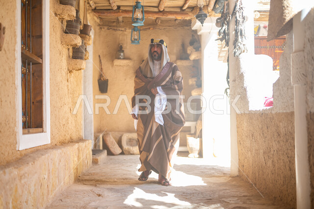 يوم بدينا 1727 م، الفخر والاعتزاز بالهوية السعودية، المناسبات والأعياد الوطنية، رجل عربي خليجي سعودي يرتدي العقال والبشت التقليدي في منزل طيني قديم، ارتداء الأزياء الشعبية في ذكرى تأسيس الدولة السعودية الاولى 22 فبراير