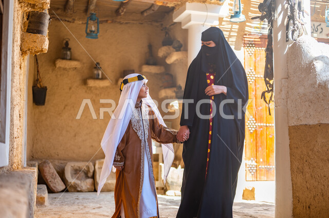 تربيه الأبناء على حب الوطن، تبادل الأحاديث والدردشات، ذكرى تأسيس الدولة السعودية 1727 م، امرأة عربيه خليجيه سعوديه ترتدي البرقع والعباءه السوداء تمسك بيد ابنها وتمشي في إحدى البيوت التراثيه القديمة، ارتداء الأزياء الشعبيه التقليدية في المناسبات والأعياد الوطنية