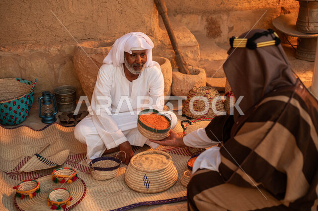 الاعتزاز بالتراث السعودي، رجل يقوم بالشراء من بائع عربي خليجي سعودي يرتدي الزي التقليدي يقوم ببيع العدس و البقوليات على بساط شعبي ،عرض المنتجات و الحبوب المحليه الوطنيه في سلل من الحصير اليدوي ،يوم بدينا 22 فبراير، ذكرى تأسيس الدولة السعودية الأولى 1727 م