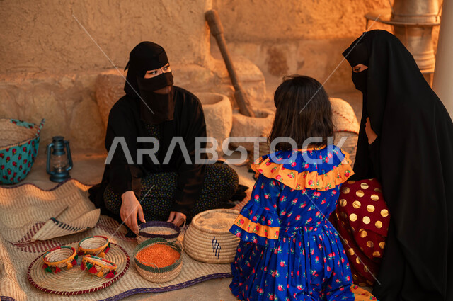 ذكرى يوم تأسيس الدولة السعودية الأولى 22 فباير، عرض المنتجات والحبوب المحليه الوطنيه في سلل من الحصير اليدوي ،إمرأه مع ابنتها تقوم بالشراء من بائعه عربية خليجية سعودية ترتدي البرقع والعباءة السوداء تقوم ببيع العدس و البقوليات على بساط شعبي، يوم بدينا 1727 م