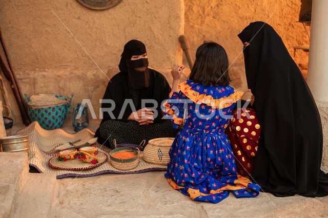 عرض المنتجات والحبوب المحليه الوطنيه في سلل من الحصير اليدوي ،إمرأه مع ابنتها تقوم بالشراء من بائعه عربية خليجية سعودية ترتدي البرقع والعباءة السوداء تقوم ببيع العدس و البقوليات على بساط شعبي، ذكرى يوم تأسيس الدولة السعودية الأولى 22 فباير،  يوم بدينا 1727 م