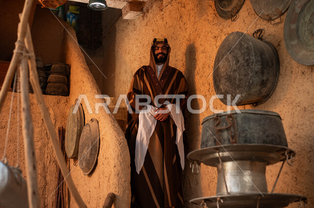 ذكرى تأسيس الدولة السعودية الاولى 22 فبراير ،يوم بدينا 1727 م ،الوقوف على درج مبني من الطين في احد البيوت التراثية، ارتداء الأزياء الشعبيه في الأعياد الوطنية ،رجل عربي خليجي سعودي يرتدي الزي التقليدي  يقف بايماءات أيدي متماسكة وينظر الى الكاميرا بتعابير السرور